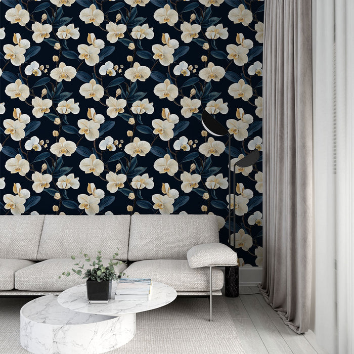 Un salon élégant avec un papier peint floral aux grandes orchidées blanches sur fond bleu marine, créant une atmosphère apaisante et raffinée.