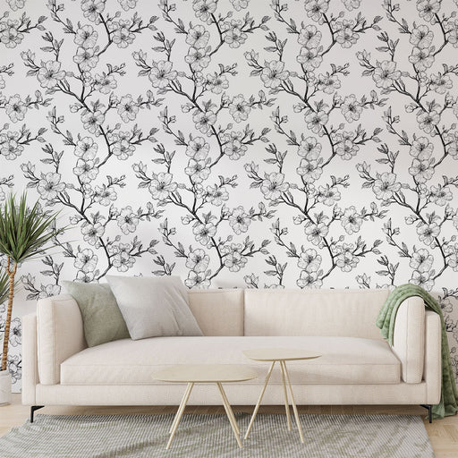 Un salon élégant avec un papier peint floral noir et blanc représentant des branches de fleurs délicates, créant une atmosphère douce et apaisante.