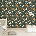 Une chambre moderne avec un papier peint floral vert foncé orné de papillons orange et de fleurs blanches, créant une atmosphère vivante et apaisante.