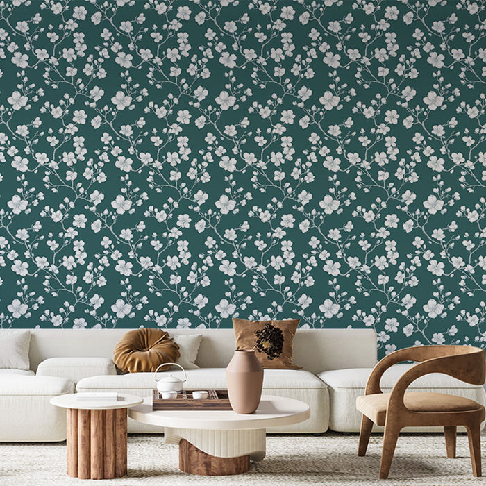Un salon élégant avec un papier peint floral aux motifs blancs sur fond vert profond, créant une atmosphère apaisante et naturelle.