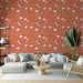 Un salon lumineux avec un papier peint terracotta orné de motifs floraux blancs, créant une atmosphère chaleureuse et accueillante.