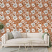 Un salon moderne avec un papier peint floral aux teintes chaudes de terre cuite, orné de fleurs blanches et roses, créant une ambiance accueillante et douce.