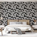 Une chambre élégante avec un papier peint floral noir et blanc, présentant des motifs de fleurs délicates qui créent une atmosphère à la fois moderne et apaisante.