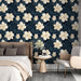 Une chambre moderne avec un papier peint floral sur fond bleu nuit, mettant en valeur de grandes fleurs crème et des feuilles délicates, créant une ambiance apaisante et élégante.