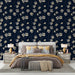 Une chambre élégante avec un papier peint floral bleu nuit et doré, présentant des motifs de fleurs délicates qui créent une ambiance chaleureuse et raffinée.