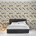 Une chambre moderne avec un papier peint floral aux motifs noirs et dorés sur fond crème, créant une atmosphère élégante et chaleureuse.