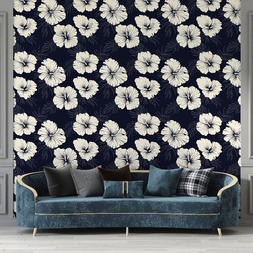Un salon élégant avec un papier peint floral bleu marine orné de grandes fleurs blanches, créant une ambiance tropicale et apaisante.