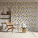 Une pièce lumineuse avec un papier peint floral aux motifs de fleurs jaunes et noires sur fond clair, créant une atmosphère chaleureuse et accueillante.