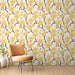 Une chambre lumineuse avec un papier peint floral aux grandes fleurs jaunes sur fond clair, créant une atmosphère joyeuse et accueillante.
