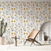 Une pièce lumineuse avec un papier peint floral aux motifs jaunes et gris sur fond clair, évoquant une atmosphère joyeuse et accueillante.