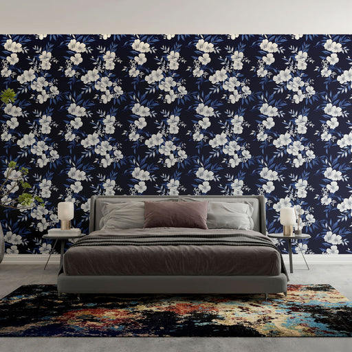 Une chambre élégante avec un papier peint floral sur fond bleu nuit, aux motifs de fleurs blanches et feuillages, créant une atmosphère apaisante et raffinée.