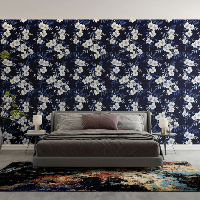 Une chambre élégante avec un papier peint floral sur fond bleu nuit, aux motifs de fleurs blanches et feuillages, créant une atmosphère apaisante et raffinée.
