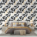 Une chambre élégante avec un papier peint floral noir, blanc et doré, mêlant des motifs de feuilles et de baies, créant une ambiance moderne et chaleureuse.