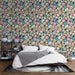 Une chambre moderne avec un papier peint floral aux motifs colorés de fleurs roses, bleues et crème sur fond clair, créant une atmosphère joyeuse et accueillante.