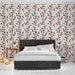Une chambre moderne avec un papier peint floral aux motifs de branches bleues et baies rouges sur fond clair, créant une ambiance chaleureuse et accueillante.