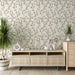 Une pièce moderne avec un papier peint floral beige orné de délicates branches noires, créant une atmosphère apaisante et élégante.