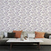 Un salon élégant avec un papier peint floral aux motifs de feuilles violettes et beige sur fond clair, créant une ambiance douce et apaisante.