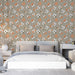 Une chambre moderne avec un papier peint floral aux motifs colorés d'orange et de blanc sur fond beige, créant une atmosphère chaleureuse et accueillante.