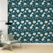 Une chambre moderne avec un papier peint floral sur fond vert profond, illustrant de grandes fleurs blanches et des touches délicates de végétation, créant une atmosphère apaisante et élégante.