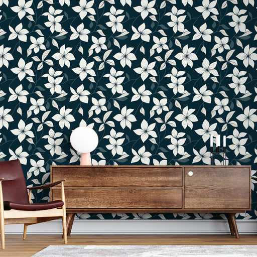 Un salon contemporain avec un papier peint floral sur fond bleu nuit, présentant de grandes fleurs blanches et des feuilles délicates, créant une ambiance apaisante et élégante.