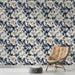 Un salon élégant avec un papier peint floral aux motifs en relief dans des teintes de bleu, crème et noir, créant une ambiance sophistiquée et apaisante.