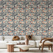 Un salon élégant avec un papier peint floral beige et bleu marine, orné de délicates branches et de fleurs corail, créant une ambiance chaleureuse et accueillante.