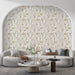 Un salon moderne avec un papier peint floral beige et doré, illustrant des motifs délicats de fleurs et de feuillages, créant une ambiance chaleureuse et apaisante.