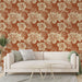 Un salon lumineux avec un papier peint floral aux grandes fleurs crème sur fond terracotta, créant une ambiance chaleureuse et tropicale.
