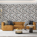 Un salon moderne avec un papier peint floral aux motifs noirs et orange sur fond blanc, créant une atmosphère dynamique et accueillante.