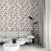 Un salon moderne avec un papier peint floral sur fond rose pâle, orné de motifs noirs délicats qui créent une atmosphère élégante et apaisante.