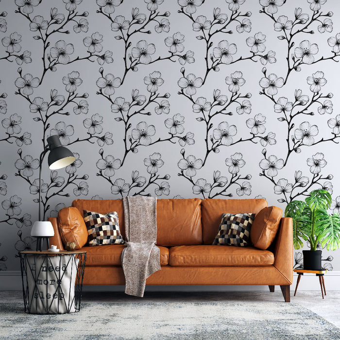 Un salon moderne avec un papier peint floral noir et blanc représentant des branches délicates de fleurs sur fond gris, créant une atmosphère douce et élégante.