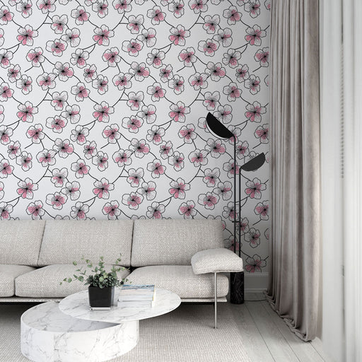 Un salon moderne avec un papier peint floral aux motifs de fleurs roses et noires sur fond blanc, créant une ambiance douce et accueillante.