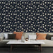 Un salon élégant avec un papier peint floral sur fond bleu nuit, aux motifs délicats de fleurs blanches, créant une atmosphère apaisante et raffinée.