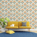 Un salon lumineux avec un papier peint floral aux motifs de fleurs orange et vert sur fond crème, créant une atmosphère chaleureuse et accueillante.