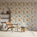 Un salon lumineux avec un papier peint floral aux motifs de fleurs orange et bleu sur fond crème, créant une ambiance douce et accueillante.