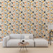 Un salon moderne avec un papier peint floral aux motifs de feuilles stylisées en noir, orange et jaune sur fond clair, créant une ambiance chaleureuse et accueillante.