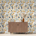 Une pièce moderne avec un papier peint floral aux motifs de feuilles et de fruits dans des teintes jaunes, vertes et noires, créant une ambiance chaleureuse et accueillante.