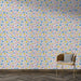 Une pièce lumineuse avec un papier peint floral aux motifs colorés de fleurs bleues, roses et jaunes sur fond blanc, créant une ambiance joyeuse et fraîche.