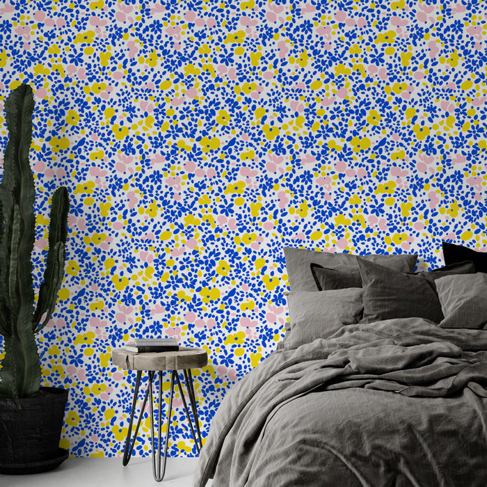 Une chambre moderne avec un papier peint floral coloré aux motifs de fleurs roses, jaunes et bleues sur fond blanc, créant une atmosphère joyeuse et dynamique.