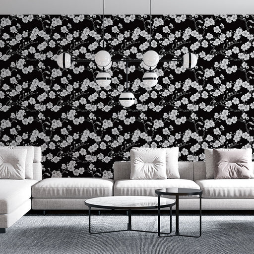 Un salon moderne avec un papier peint floral noir et blanc présentant des branches délicates, créant une ambiance élégante et contemporaine.