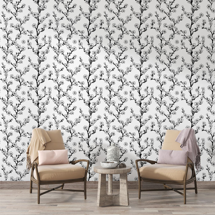Un salon élégant avec un papier peint floral noir et blanc représentant des branches délicates, créant une atmosphère douce et apaisante.