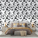 Une chambre élégante avec un papier peint noir et blanc représentant des branches fleuries, créant une atmosphère artistique et apaisante.