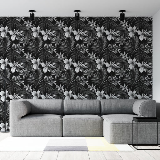 Un salon moderne avec un papier peint tropical noir et blanc aux motifs de feuilles et fleurs exotiques, créant une ambiance élégante et dynamique.