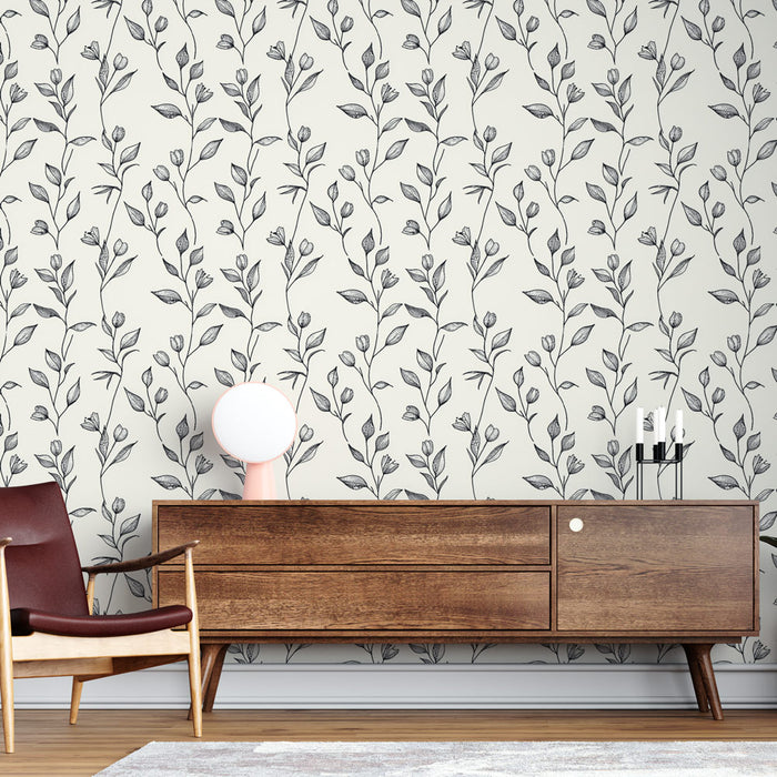 Un salon élégant avec un papier peint floral noir et blanc représentant des tiges et des fleurs délicates sur fond clair, créant une atmosphère apaisante et raffinée.
