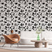 Un salon moderne avec un papier peint floral noir et blanc aux motifs délicats de feuilles, créant une ambiance élégante et contemporaine.