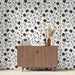 Une pièce moderne avec un papier peint floral noir, blanc et jaune, créant une atmosphère joyeuse et dynamique.