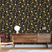 Un salon moderne avec un papier peint floral noir orné de motifs jaunes et blancs, créant une ambiance chaleureuse et accueillante.