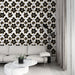 Un salon élégant avec un papier peint floral noir et doré sur fond blanc, créant une atmosphère chic et contemporaine.