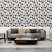 Un salon moderne avec un papier peint floral noir et orange sur fond blanc, créant une atmosphère joyeuse et accueillante.