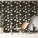 Une pièce moderne avec un papier peint floral sur fond noir, orné de grandes fleurs blanches et de touches dorées, créant une atmosphère chaleureuse et dynamique.